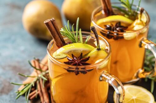 Two glasses of hot whiskey with lemon star anise and rosemary garnish